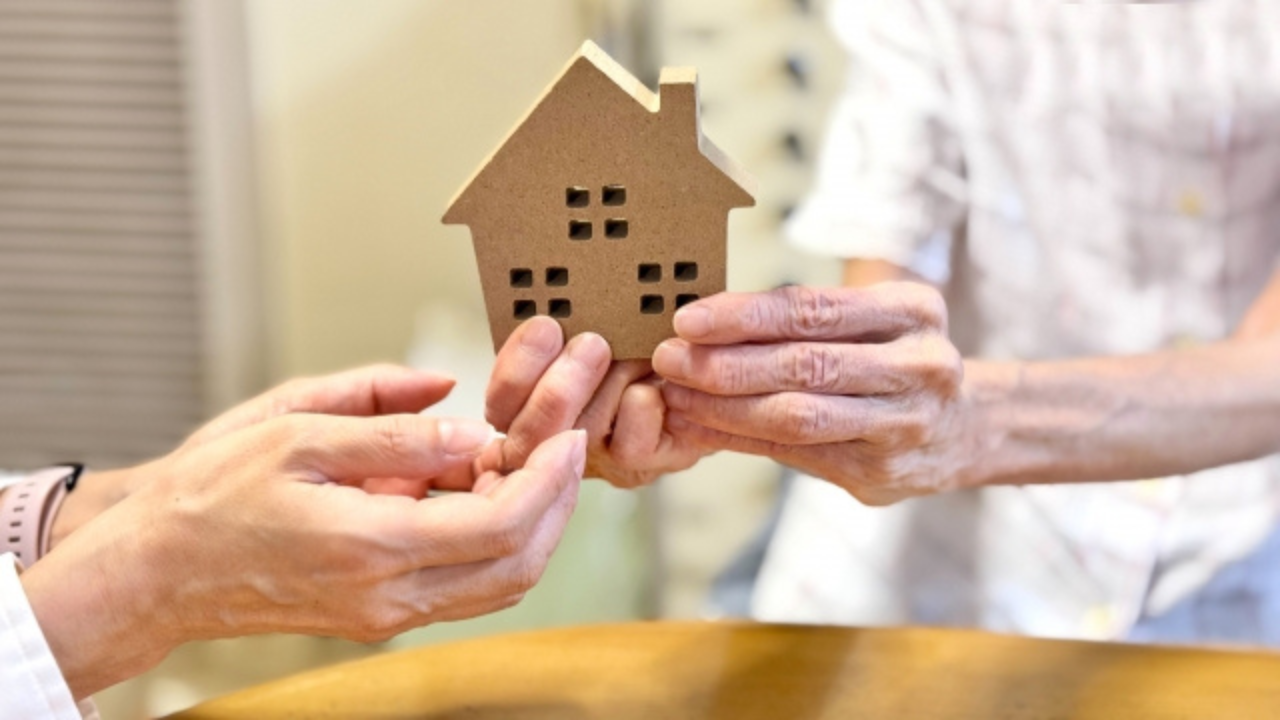 生前整理を解説した記事に使用した老人が家の模型を手渡す画像