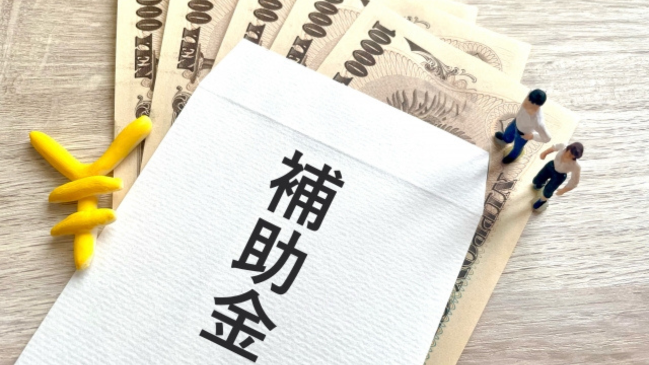 補助金等の情報お知らせ記事に使用した補助金と記された封筒の下にお札が5枚並んでいる画像